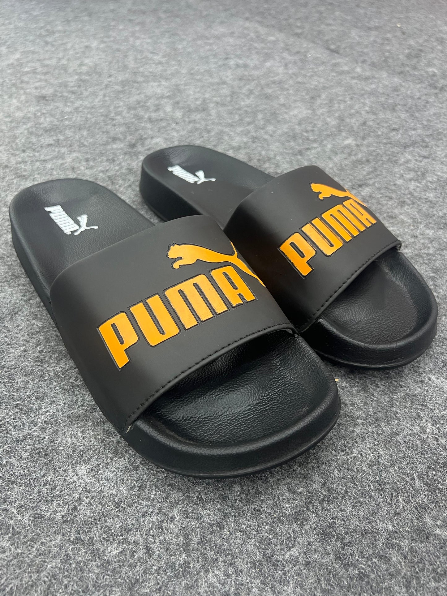 Black Puma slides with a bold yellow logo.
