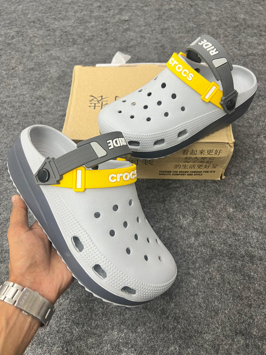 Grey Crocs featuring bold yellow and dark grey straps.
